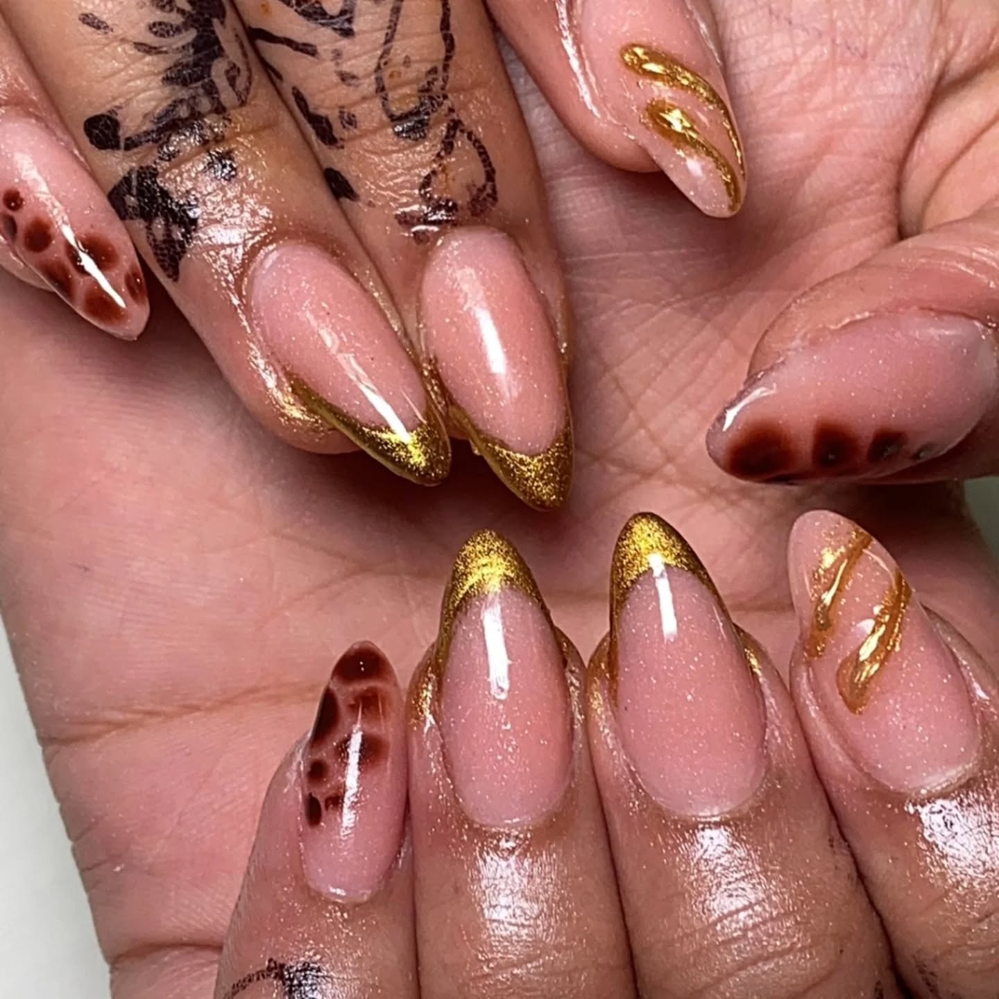 Nude almond nails with gold swirl and tortoise accent